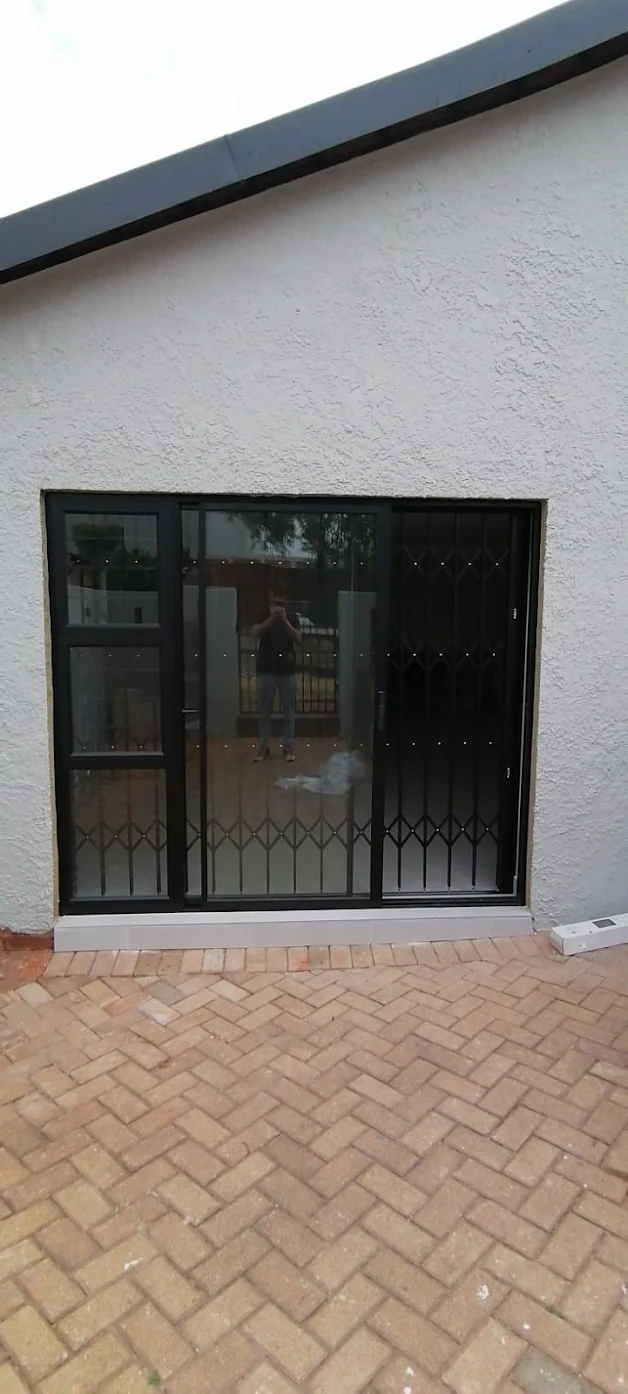 Expandable security gate installed behind sliding entry door